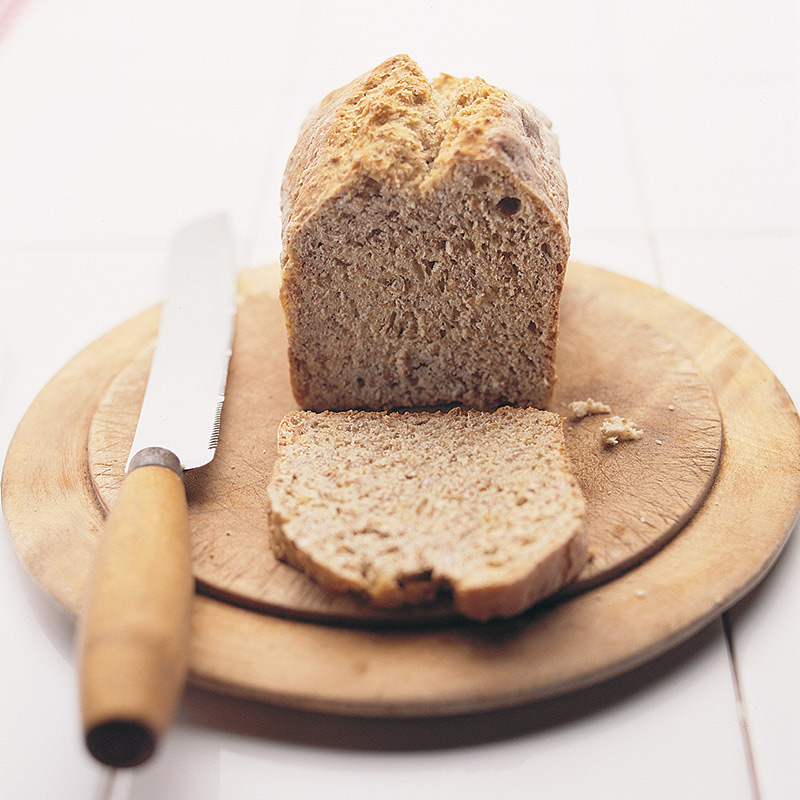Sliced loaf of bread on breadboard with a knife