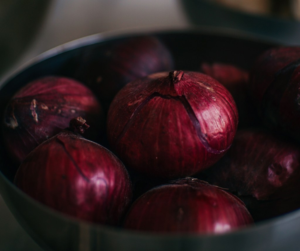 Bowl of red onions. From the outside they look lush and red, but peel them back, start exploring and your perception of what's inside is quite different.